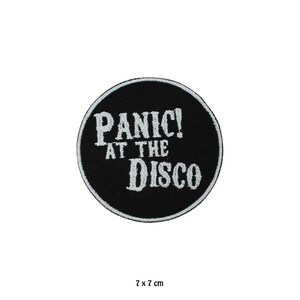 May include: A circular black embroidered patch featuring the white text PANIC! AT THE DISCO in a stylised font. The patch has a white stitched border and measures 7 cm by 7 cm. The design is centred on a plain background, showcasing the embroidery.