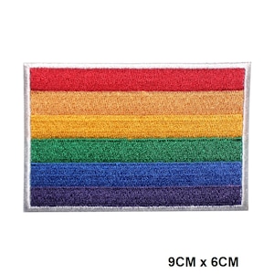 May include: A rainbow pride flag patch with red, orange, yellow, green, blue, and purple stripes. The patch is 9 cm by 6 cm and has a white border.