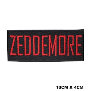 May include: A rectangular black embroidered patch featuring the name ZEDDEMORE stitched in bold red capital letters. The patch has a clean, finished border and measures 10 cm by 4 cm, as indicated by the text printed below the item.