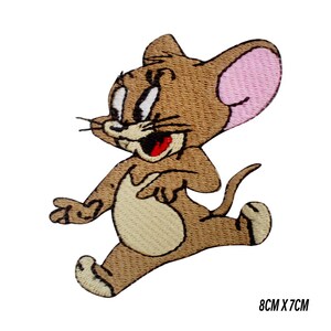 May include: Embroidered patch featuring Jerry the mouse from Tom and Jerry. The patch is brown with a light tan belly and pink inner ears. The mouse is in a running pose with a wide, excited expression. The patch measures 8cm x 7cm.
