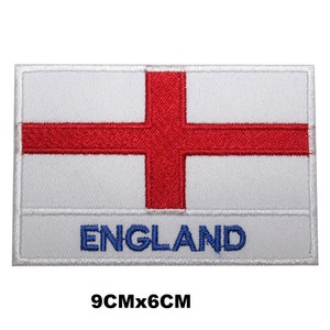 May include: Embroidered patch of the English flag, a white rectangle with a red cross. The word "ENGLAND" is embroidered in blue at the bottom. The patch measures 9cm x 6cm.
