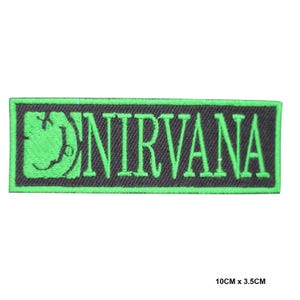 May include: A rectangular embroidered patch featuring a black background with a bright green border. The patch displays a green stylized smiley face icon on the left and the text NIRVANA in green capital letters. It measures 10 cm by 3.5 cm.