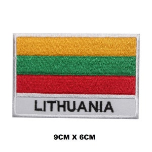 May include: An embroidered iron-on patch featuring the Lithuanian flag with yellow, green, and red stripes. The patch is white with a gray border and the word "LITHUANIA" in black text. The patch measures 9 cm by 6 cm.