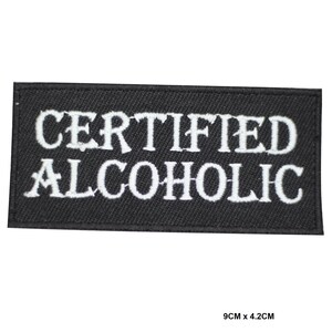 May include: Black embroidered patch with white text that reads "CERTIFIED ALCOHOLIC". The patch is 9 cm by 4.2 cm.