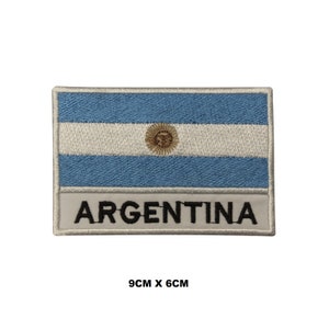 May include: Embroidered patch featuring the Argentinian flag with the words "ARGENTINA" below. The flag is blue and white with a yellow sun in the centre. The patch is 9 cm by 6 cm.