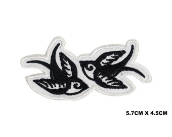 May include: White embroidered patch with two black swallows facing each other. The patch measures 5.7cm by 4.5cm.