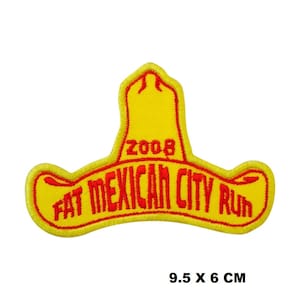 Può includere: Toppa ricamata gialla con contorno rosso, a forma di sombrero. La toppa dice "Fat Mexican City Run 2008" e misura 9,5 x 6 cm.
