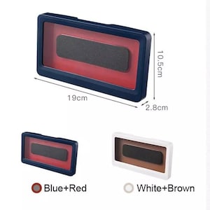 Puede incluir: Dos soportes para teléfono con un frente transparente y un marco de color. El soporte de la izquierda es azul con un interior rojo y el soporte de la derecha es blanco con un interior marrón. Ambos soportes miden 10,5 cm de alto, 19 cm de ancho y 2,8 cm de profundidad.  Azul+Rojo y Blanco+Marrón.