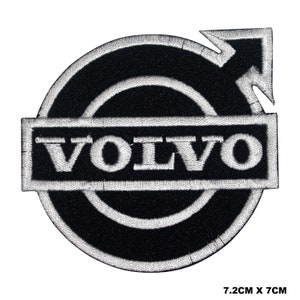 Puede incluir: Parche de hierro bordado en blanco y negro con el logotipo de Volvo. El logotipo presenta un círculo con una flecha apuntando hacia la derecha y la palabra "VOLVO" en un rectángulo blanco.