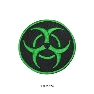 Könnte beinhalten: Grüner Biohazard-Symbol-Stickerei-Aufnäher auf schwarzem Hintergrund. Der Aufnäher ist rund und hat einen Durchmesser von 7 cm.