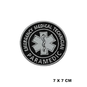 May include: Black and white embroidered patch with the text "Emergency Medical Technician Paramedic" and a white star of life symbol. The patch is 7 cm by 7 cm.