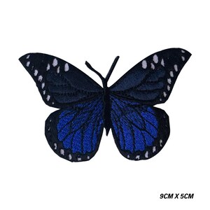 May include: Embroidered butterfly patch in shades of blue and black. The butterfly has a detailed wing pattern with white accents. The patch measures 9cm by 5cm.