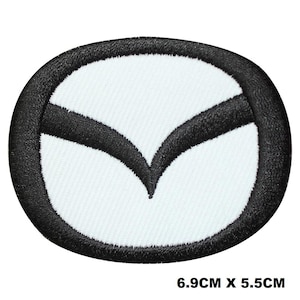 May include: Embroidered patch with the Mazda logo. The patch has a white oval background with a black border. The Mazda logo is black and is in the centre of the patch. The patch measures 6.9cm x 5.5cm.