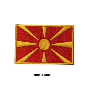 May include: A red embroidered patch with a yellow sun and 16 rays. The patch is 9 inches by 6 inches.