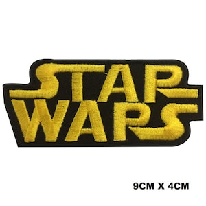 May include: An embroidered patch featuring the yellow Star Wars logo on a black background. The patch has a rectangular shape with rounded edges and measures 9 cm by 4 cm as indicated by the text printed in the bottom right corner of the image.