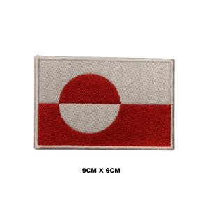 Puede incluir: Un parche bordado con la bandera de Groenlandia. La bandera es blanca con un círculo rojo y una franja horizontal roja en la parte inferior. El parche mide 9 cm por 6 cm.