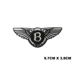 Peut inclure: Écusson brodé noir et blanc avec un emblème ailé et la lettre "B" au centre. Mesure 9,7 cm x 3,9 cm. Le design présente des motifs d'ailes détaillés et un bord circulaire. Idéal pour les vêtements et accessoires.
