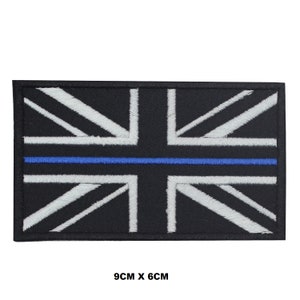 Può includere: Un patch ricamato con la bandiera Union Jack in bianco e nero con una sottile linea blu al centro. Il patch misura 9 cm x 6 cm.