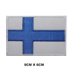May include: Embroidered patch of the Finnish flag. The flag is white with a blue cross. The patch is 9 cm by 6 cm.