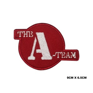 Może przedstawiać: Czerwona naszywka haftowana z napisem "THE A-TEAM" w kolorze białym. Naszywka ma wymiary 9 cm x 6,5 cm.