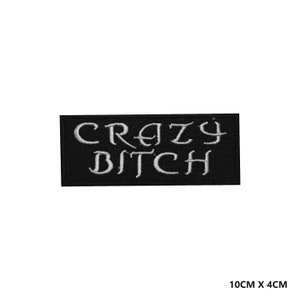May include: A black rectangular patch with the words "CRAZY BITCH" embroidered in white. The patch measures 10cm x 4cm.