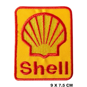 Puede incluir: Un parche bordado amarillo y rojo con el logotipo de Shell. El logotipo es una concha amarilla con contornos rojos y la palabra "Shell" en letras rojas. El parche mide 9 por 7,5 centímetros.