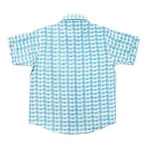 Puede incluir: Una camisa blanca de manga corta con botones y estampado de elefantes azules.