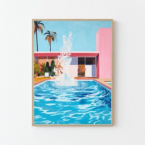 May include: A framed art print depicts a vibrant pool scene. The artwork features a turquoise pool with a water fountain, a pink building, palm trees, and a bright blue sky. The print is encased in a light brown wooden frame.
