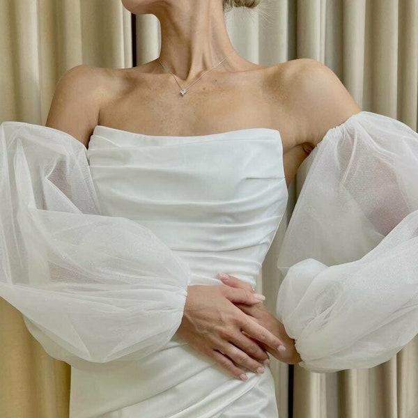 Removable puffy sleeves made of shiny tulle for a wedding dress have the appearance of puffy sleeves with an elastic band.