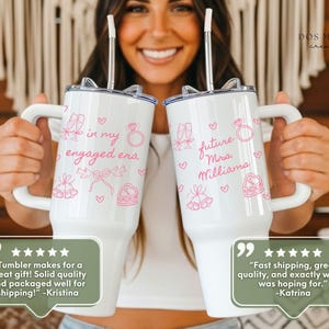 Puede incluir: Dos vasos t&eacute;rmicos blancos de acero inoxidable con asa y pajita, decorados con dibujos lineales rosas de copas de champ&aacute;n, anillos de compromiso, campanas y corazones. El texto dice "in my engaged era" y "future Mrs. Williams".