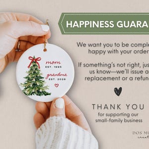 May include: A round white ceramic ornament featuring a watercolor Christmas tree with a red bow, the text mom EST. 1995, grandma EST. 2026, and a small red heart. The text HAPPINESS GUARANTEE, We want you to be completely happy with your order.