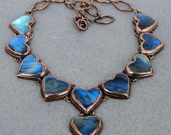 May include: A copper necklace with a chain and multiple heart-shaped labradorite stones. The stones are a deep blue with iridescent flashes of color.