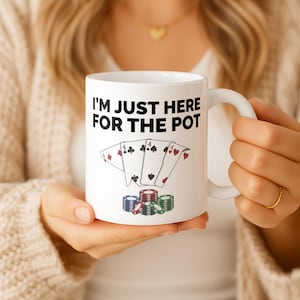 Könnte beinhalten: Weiße Keramik-Kaffeetasse mit dem Text "I'M JUST HERE FOR THE POT". Die Tasse hat ein Poker-Thema mit Spielkarten und Stapeln von Pokerchips in Rot, Blau und Grün.