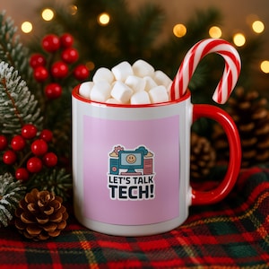 May include: A white ceramic mug with a red rim and handle, filled with white marshmallows and a red and white candy cane. The mug features a light purple square graphic with a computer icon, a smiley face, and the text LET'S TALK TECH!