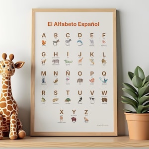 Puede incluir: Un cuadro enmarcado del alfabeto español con ilustraciones de animales, una jirafa de peluche y una planta en maceta. El cuadro muestra el alfabeto con imágenes de animales correspondientes. La jirafa es marrón y crema. La planta está en una maceta de terracota.