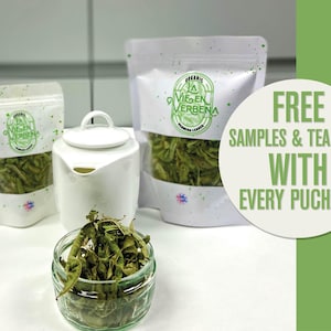 May include: Two white bags of dried green verbena tea leaves with the text "La Virgen Verbena" on the front. A white ceramic teapot and a glass jar of loose green verbena tea leaves are on a white surface. The text "FREE SAMPLES & TEA BAGS WITH EVERY PURCHASE" is on a green background.