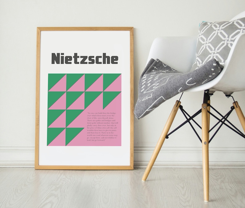 May include: A framed print with a geometric pattern of pink and green triangles. The print features the word "Nietzsche" in black text at the top and a quote from Nietzsche in smaller text below the pattern.