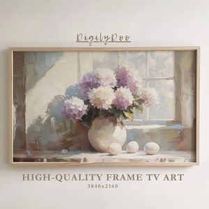 May include: A painting of a bouquet of white and purple hydrangeas in a white vase, with three white eggs on a wooden table. The painting is framed in a light wood frame.