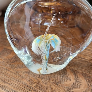 以下が含まれることがあります： 青いガラスと黄色のガラスでできたヤシの木が入ったガラス製のペーパーウェイト。ヤシの木は小さな白いガラスの泡で囲まれています。