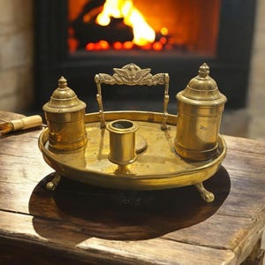 Tinteiro antigo de latão, também conhecido como standish, com caixa de areia e castiçal, provavelmente datado do século XVIII ou XIX.