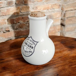 Könnte beinhalten: Weiße Keramikflasche mit einem Korkstopfen und einem Griff. Die Flasche trägt ein Etikett mit der Aufschrift "Improved Earthenware Inhaler Manufactured by J. & S.  Hall, St. London."
