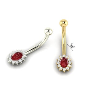 May include: A gold and silver belly button ring with a red oval gem surrounded by clear stones.