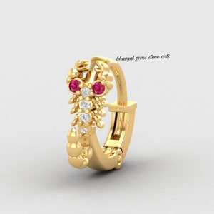 May include: Gold nose ring with a scorpion design featuring red and white gemstones. "bhavyaal gems stone art" is written in the image.