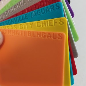 May include: A stack of colorful plastic cards with the names of different NFL teams printed on them. The top card is orange and says "Cincinnati Bengals".
