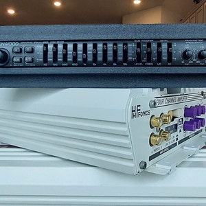 May include: A black Kenwood graphic equalizer with 10 sliders and a knob. The equalizer is on top of a white HiFonics four channel amplifier with gold and purple connectors.