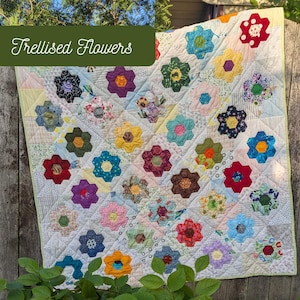 May include: A patchwork quilt with a floral design. The quilt showcases many colourful, hexagonal flowers in shades of red, blue, yellow, and purple, set against a white backdrop. The text "Trellised Flowers" is displayed on the top of the quilt.