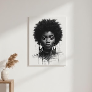 May include: Black and white portrait art print of a woman with an afro and large hoop earrings. The artwork is displayed on a white canvas, mounted on a white wall. A small wooden table and vase with dried plants are in the foreground.