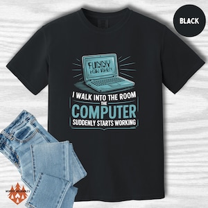May include: Black t-shirt featuring a laptop graphic and the text "FUNNY HOW WHEN I WALK INTO THE ROOM THE COMPUTER SUDDENLY STARTS WORKING." Blue jeans are visible in the lower left corner. The shirt is from "HOODSY WEARABLES."