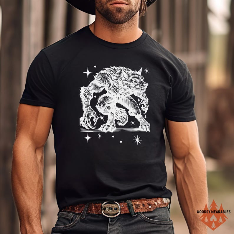 Muscular man wearing a black t-shirt with a white werewolf design, standing confidently outdoors in front of a rustic wood backdrop. He wears a wide-brimmed hat and leather belt, highlighting a tough, rugged look. The graphic features a detailed werewolf and cosmic stars.