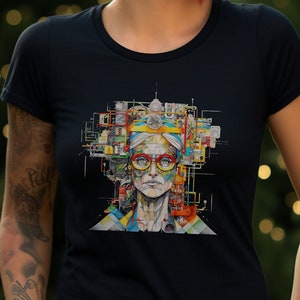May include: A woman with red hair is wearing a black t-shirt with a colorful graphic of a person's face with glasses and a headband. The graphic is made up of many different shapes and colors.